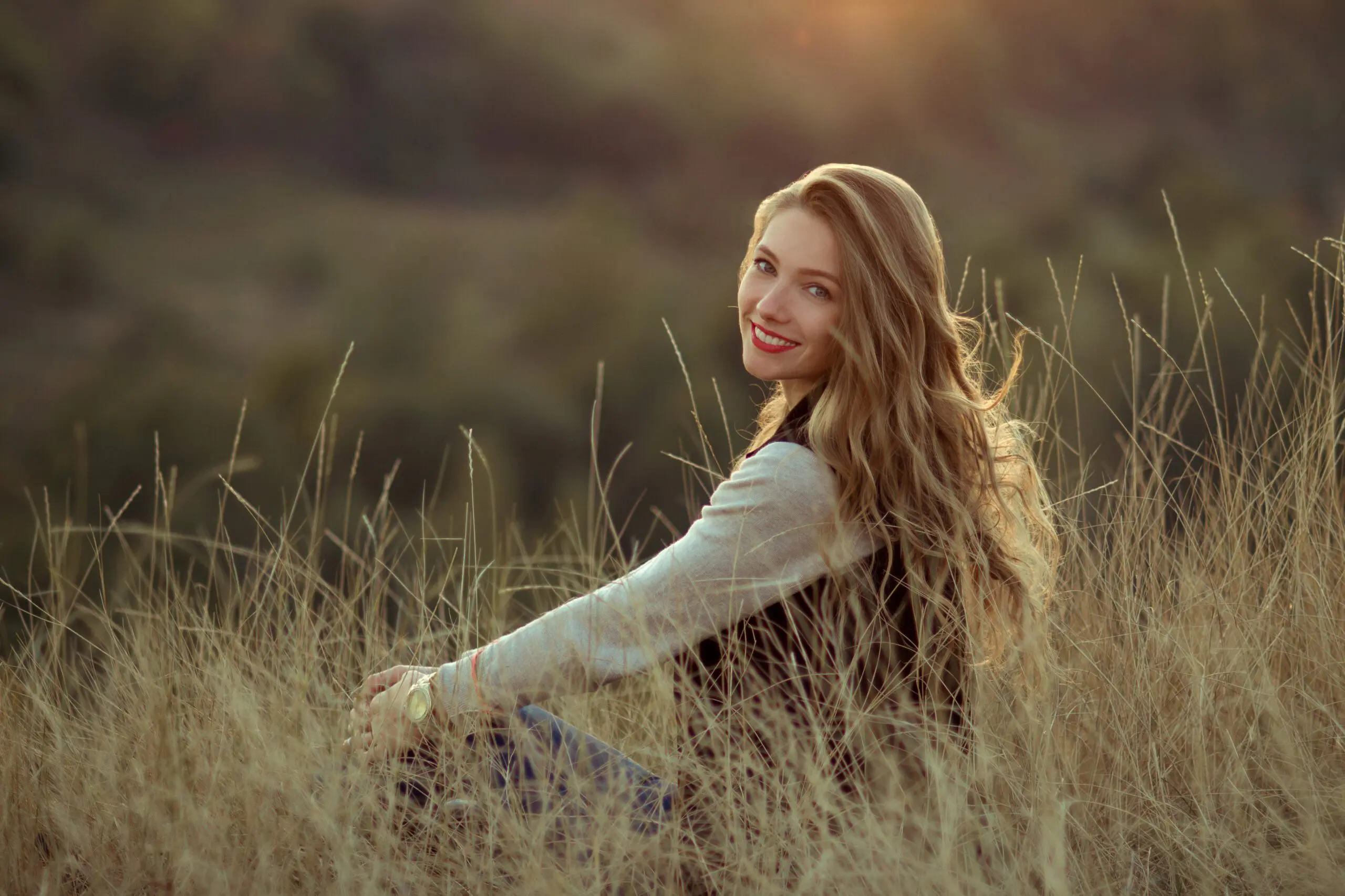 Happy cheerful joyful smiling girl sitting on the hill